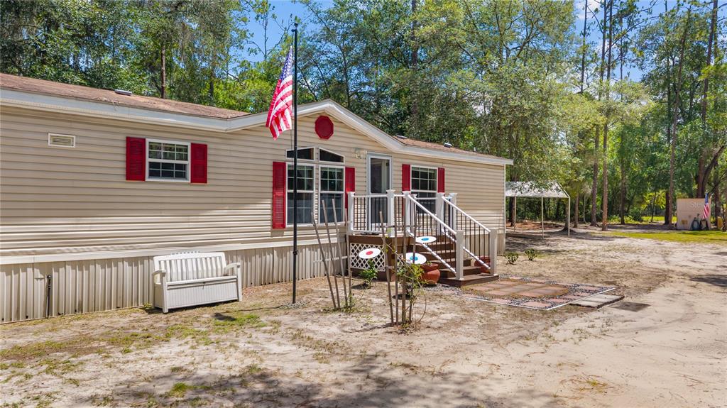 A beige mobile home with red shutters, a front porch, and an American flag pole — 106 ARROWHEAD POINT ROAD, HAWTHORNE, FL