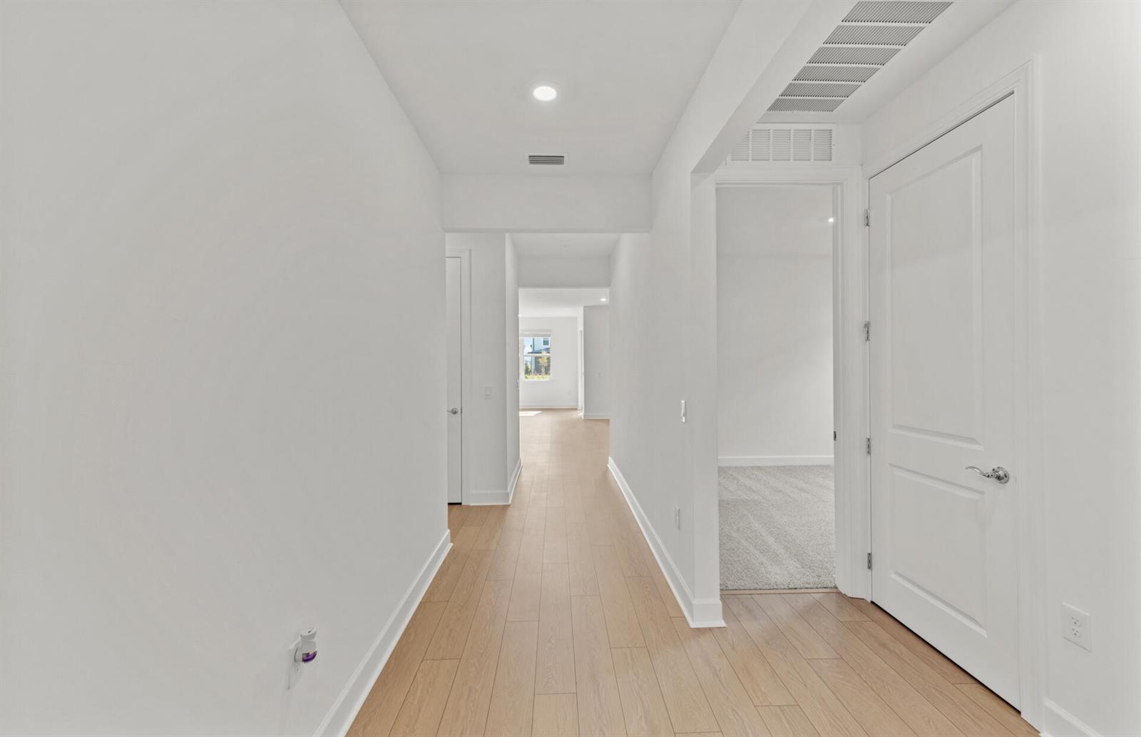 A hallway with light wood flooring leads to a room with gray carpet — 44393 Kelly Drive, Punta Gorda FL 33982, PUNTA GORDA, FL