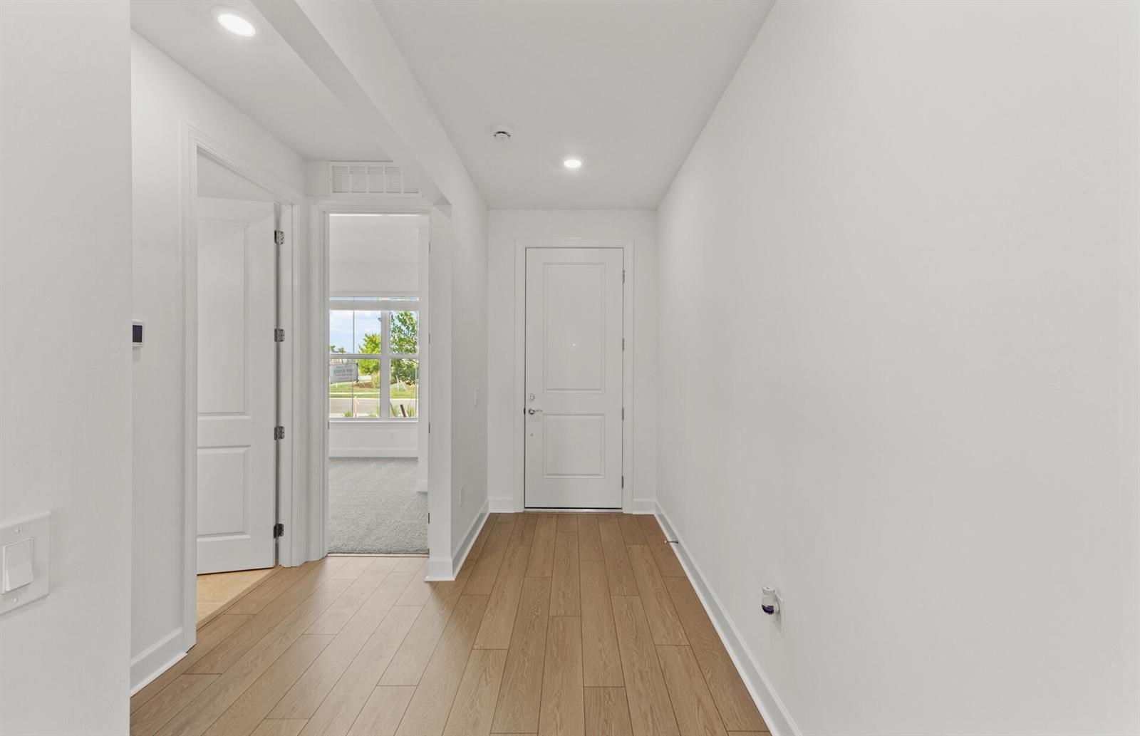 A hallway with light wood-look flooring, white walls, and two closed interior doors — 44393 Kelly Drive, Punta Gorda FL 33982, PUNTA GORDA, FL