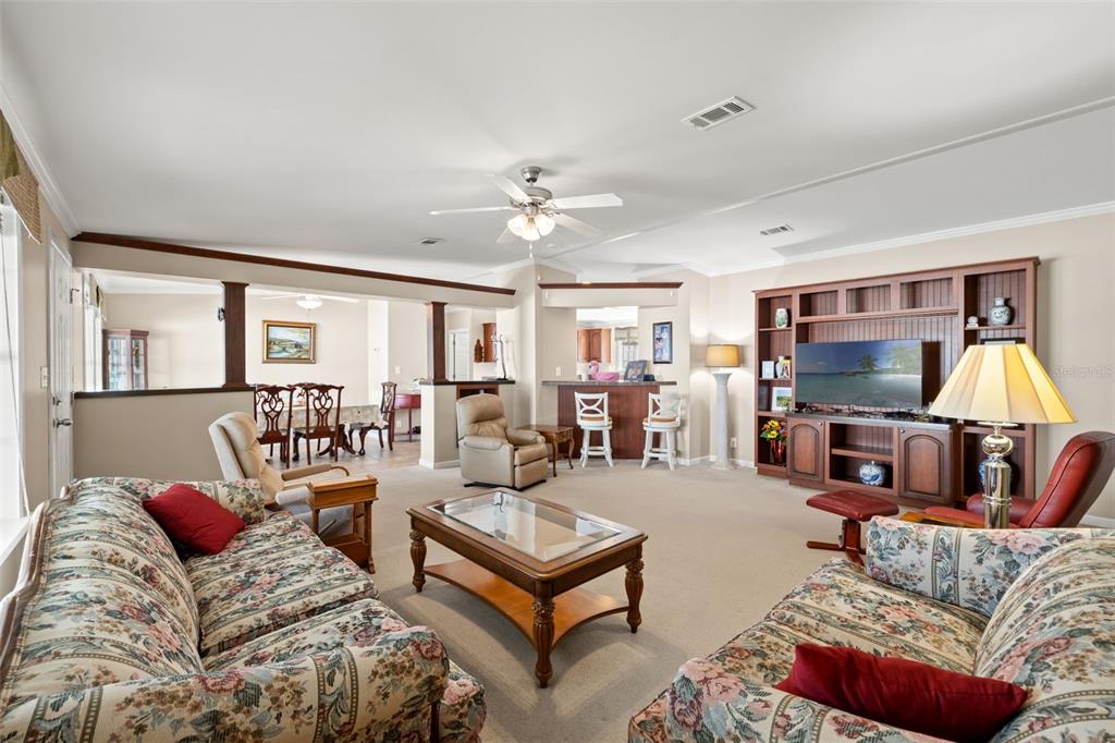 A living room features floral sofas, a wooden coffee table, and a built-in entertainment center — 82085 1ST AVENUE N UNIT 85, PINELLAS PARK, FL