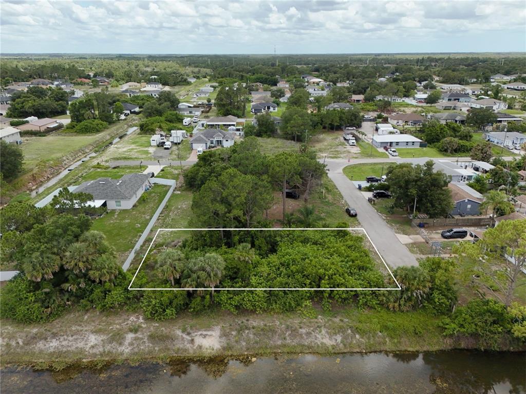 An aerial view shows a rectangular, undeveloped lot bordered by a road and a canal — 3105 BRIAN AVENUE S, LEHIGH ACRES, FL