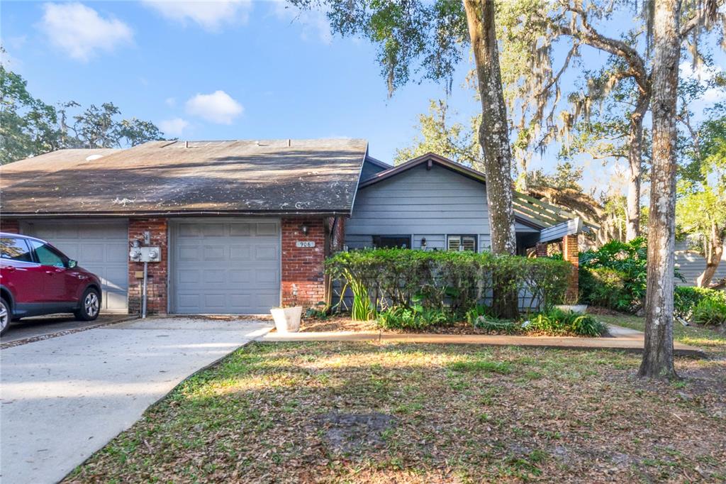 A single-story house with a brick and gray siding exterior, a garage, and a driveway — 906 VILLAGE GREEN ROAD, DELAND, FL