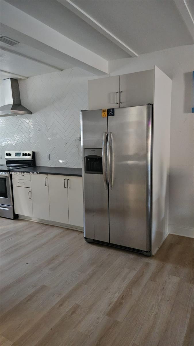 A kitchen features white cabinets, a stainless steel refrigerator, and a herringbone tile backsplash — 570 NW 97th St, Miami FL 33150, MIAMI, FL