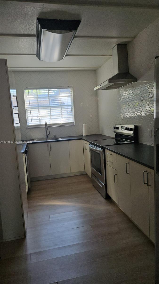 A kitchen features white cabinets, dark countertops, stainless steel appliances, and a herringbone tile backsplash — 570 NW 97th St, Miami FL 33150, MIAMI, FL
