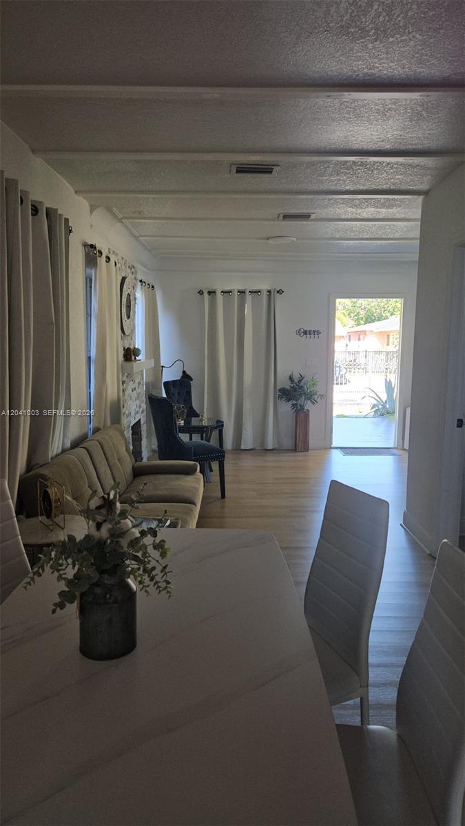 A dining area in the foreground opens into a living room with a stone fireplace — 570 NW 97th St, Miami FL 33150, MIAMI, FL