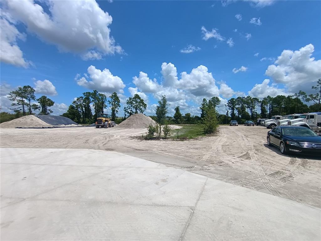 A large, unpaved construction lot features piles of dirt, heavy machinery, and parked vehicles — 6255 TAYLOR ROAD, PUNTA GORDA, FL