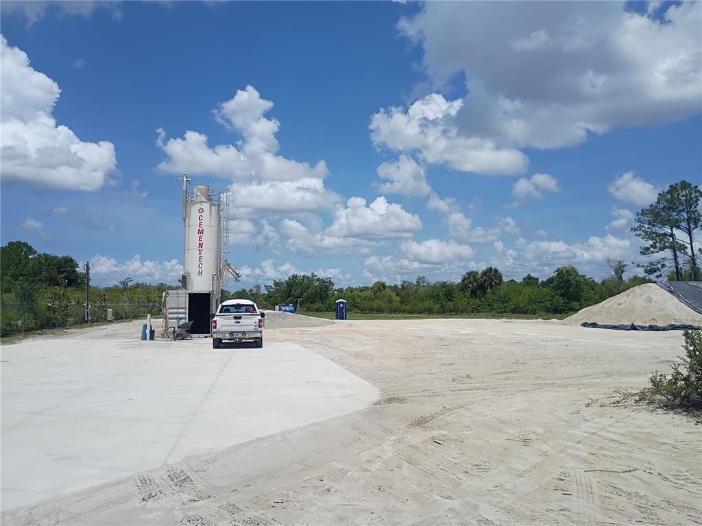 A white truck is parked next to a Cementech silo on a large, sandy lot — 6255 TAYLOR ROAD, PUNTA GORDA, FL