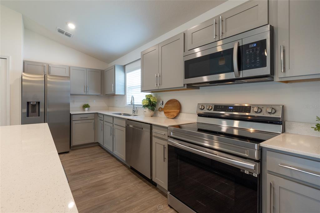 A modern kitchen features gray cabinets, stainless steel appliances, and white quartz countertops — 196 FRONTIER DRIVE, PALM COAST, FL