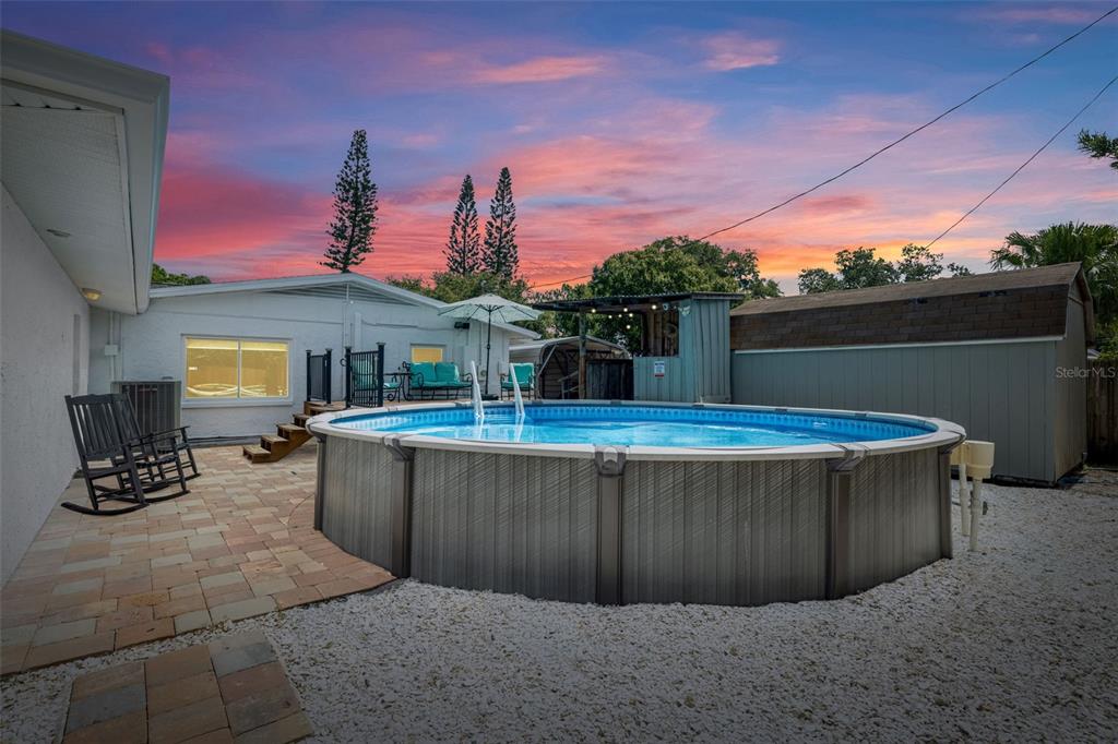 A backyard features an above-ground swimming pool, a stone patio, and a storage shed — 1224 80TH AVENUE N, ST PETERSBURG, FL