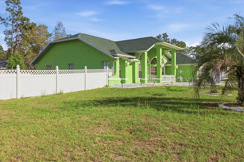 A bright green porch features a white picket fence, a chair, and a small table — 13061 SW 77TH AVENUE, OCALA, FL