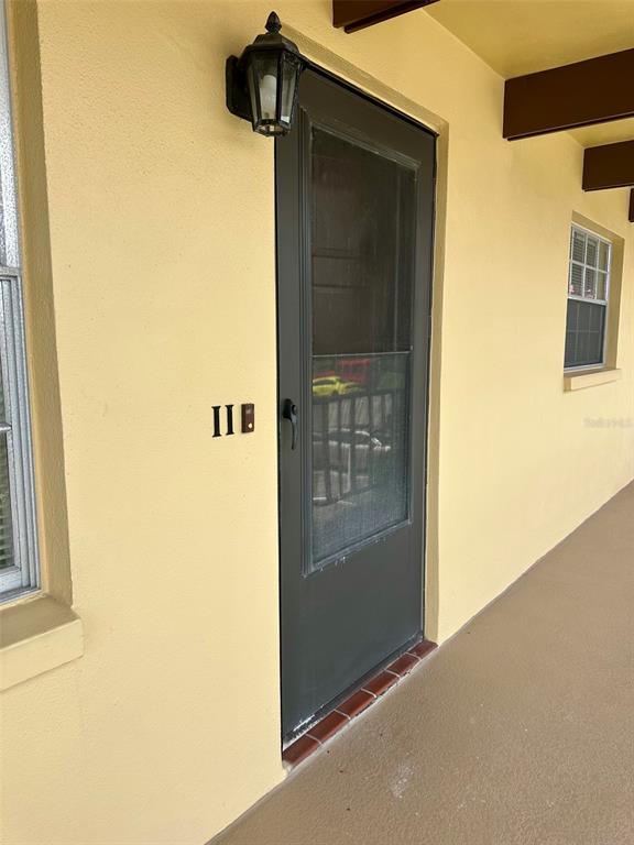 A dark storm door with a house number 11B is mounted on a yellow exterior wall — 1845 S HIGHLAND AVENUE UNIT 6-11, CLEARWATER, FL