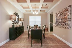 A dining room features a coffered ceiling, tile flooring, a dark sideboard, and abstract wall art — 9269 OUTLOOK ROCK TRAIL, WINDERMERE, FL