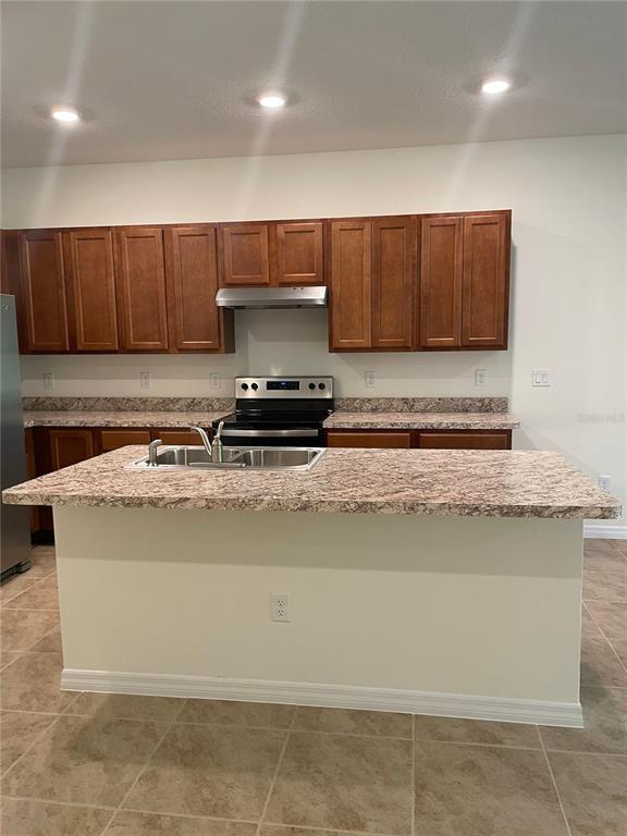 A kitchen features wood cabinets, a laminate countertop island with a sink, and tile flooring — 1249 YELLOW FINCH DRIVE, DAVENPORT, FL