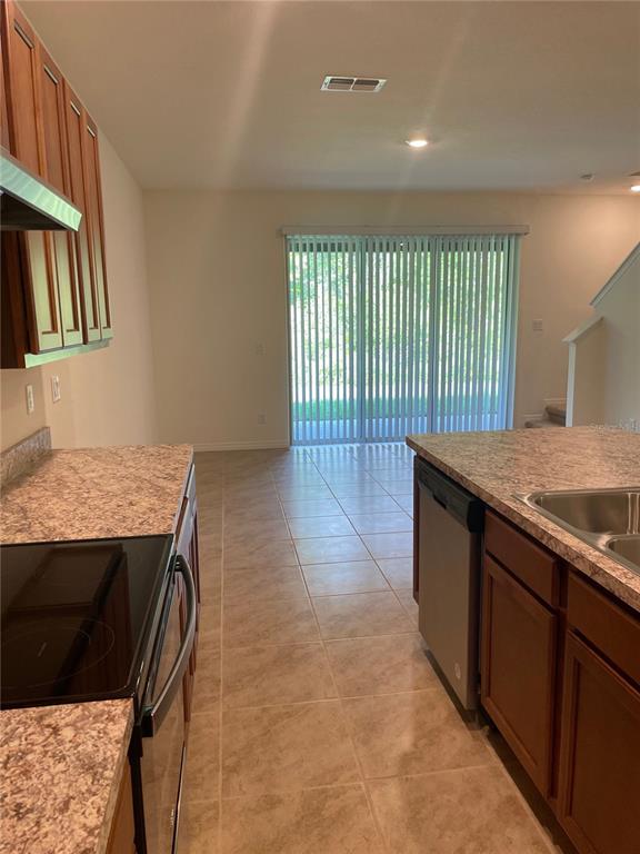 A kitchen features wood cabinets, laminate countertops, and a sliding glass door to the outside — 1249 YELLOW FINCH DRIVE, DAVENPORT, FL