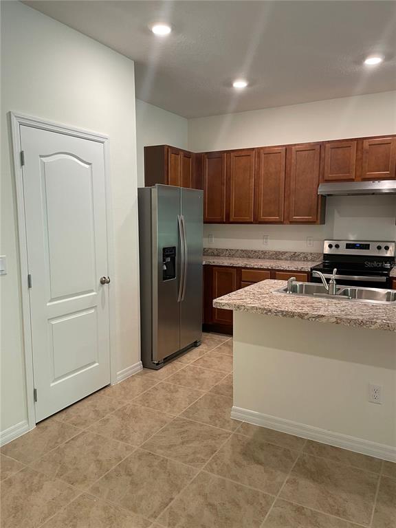 A kitchen features brown cabinets, stainless steel appliances, and a granite-topped island — 1249 YELLOW FINCH DRIVE, DAVENPORT, FL