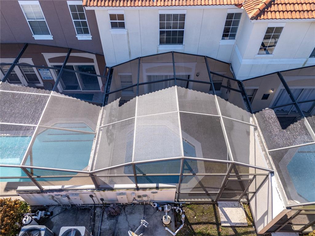 An aerial view shows a screened-in swimming pool enclosure attached to the back of a house — 4554 ALBERTO CIRCLE, KISSIMMEE, FL