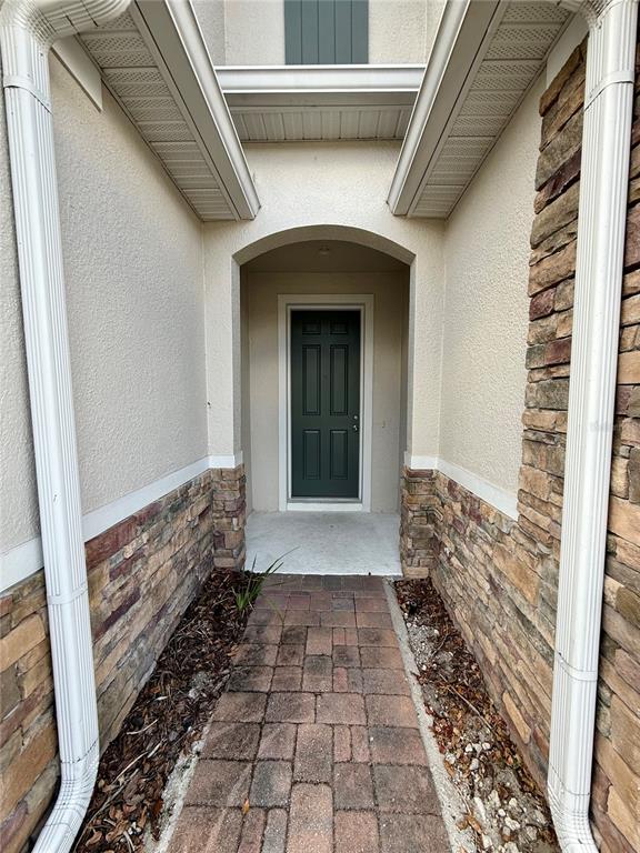 A stone-accented walkway leads to a dark green front door under a covered entryway — 7522 ALOMA PINES COURT, WINTER PARK, FL