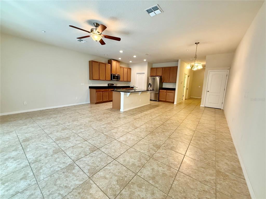A kitchen with wooden cabinets, a central island, and tile flooring opens to a living area — 7522 ALOMA PINES COURT, WINTER PARK, FL