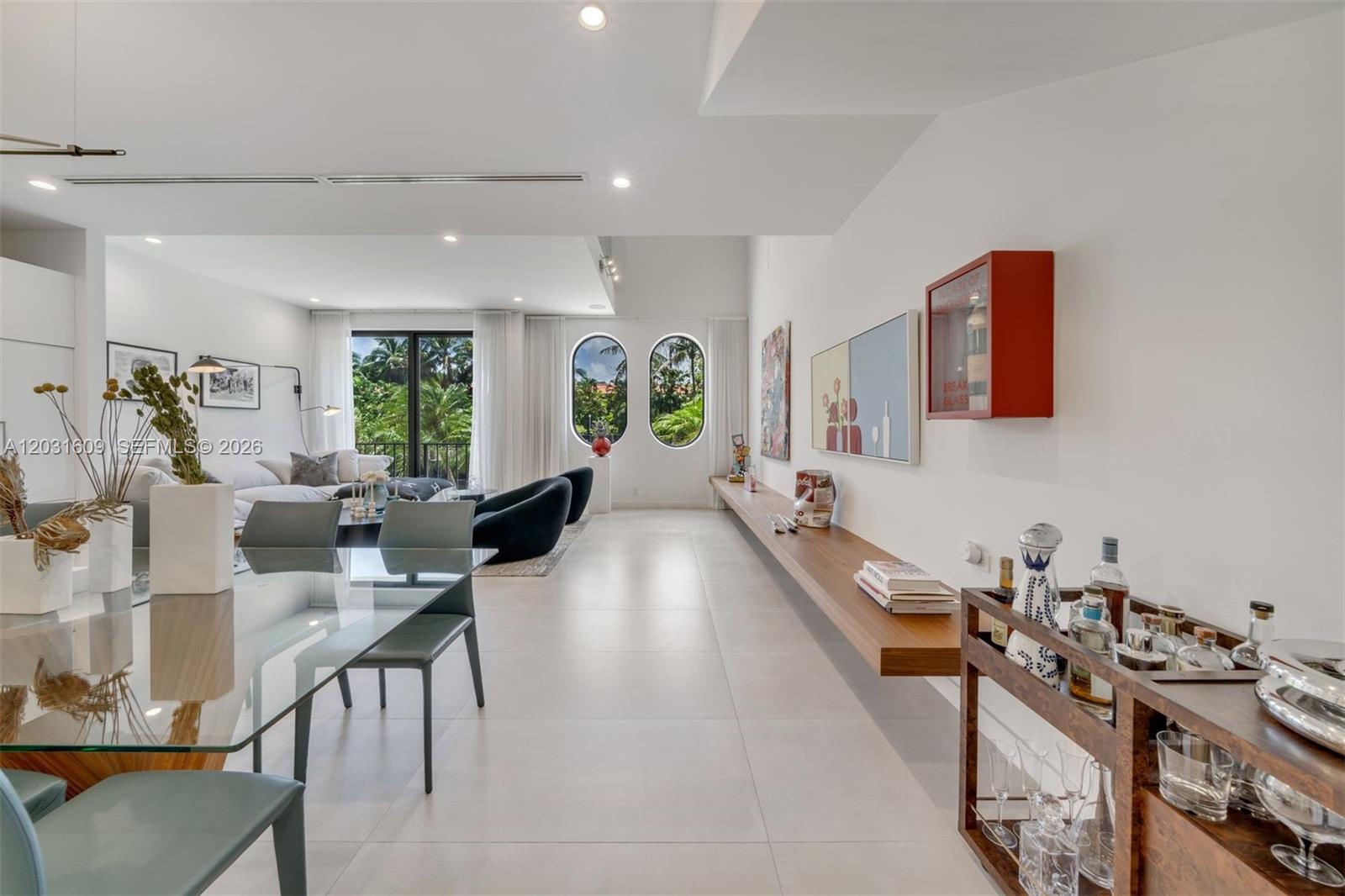 A modern living and dining area features a glass table, floating shelf, and arched windows — 10659 NE Quaybridge Ct # C5, Miami FL 33138, MIAMI, FL