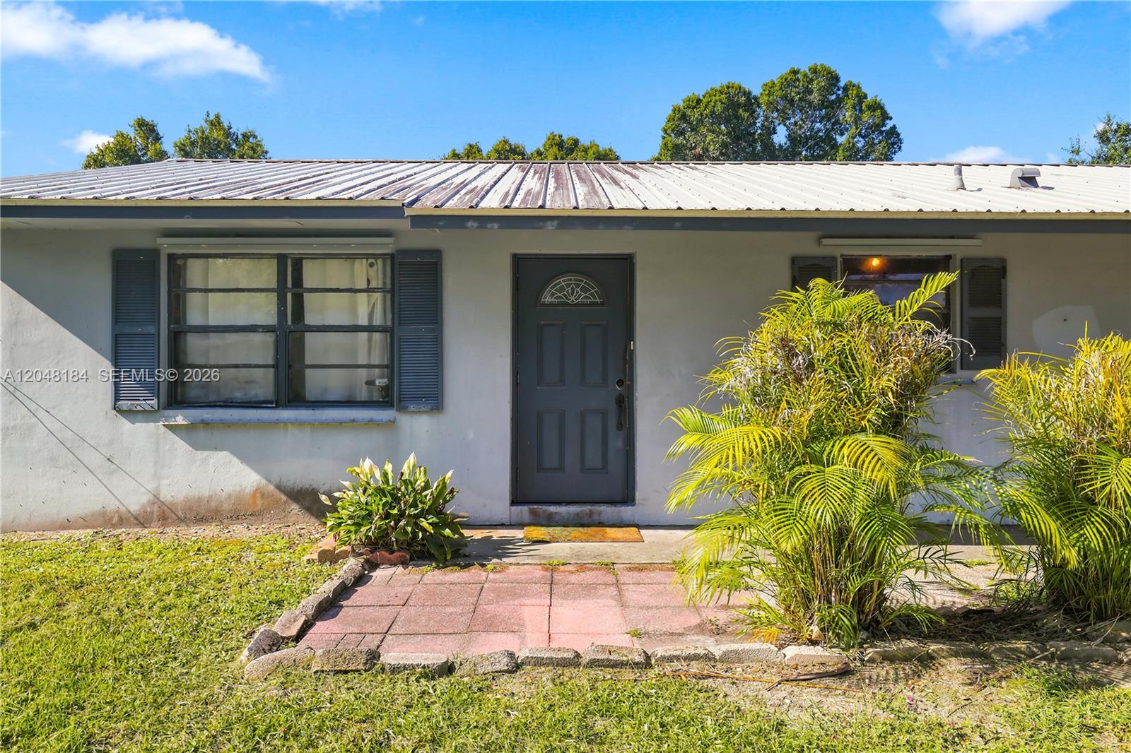 The exterior of a single-story house features a metal roof, gray siding, and a front patio — 3524 SW 17th St, Okeechobee FL 34974, OKEECHOBEE, FL
