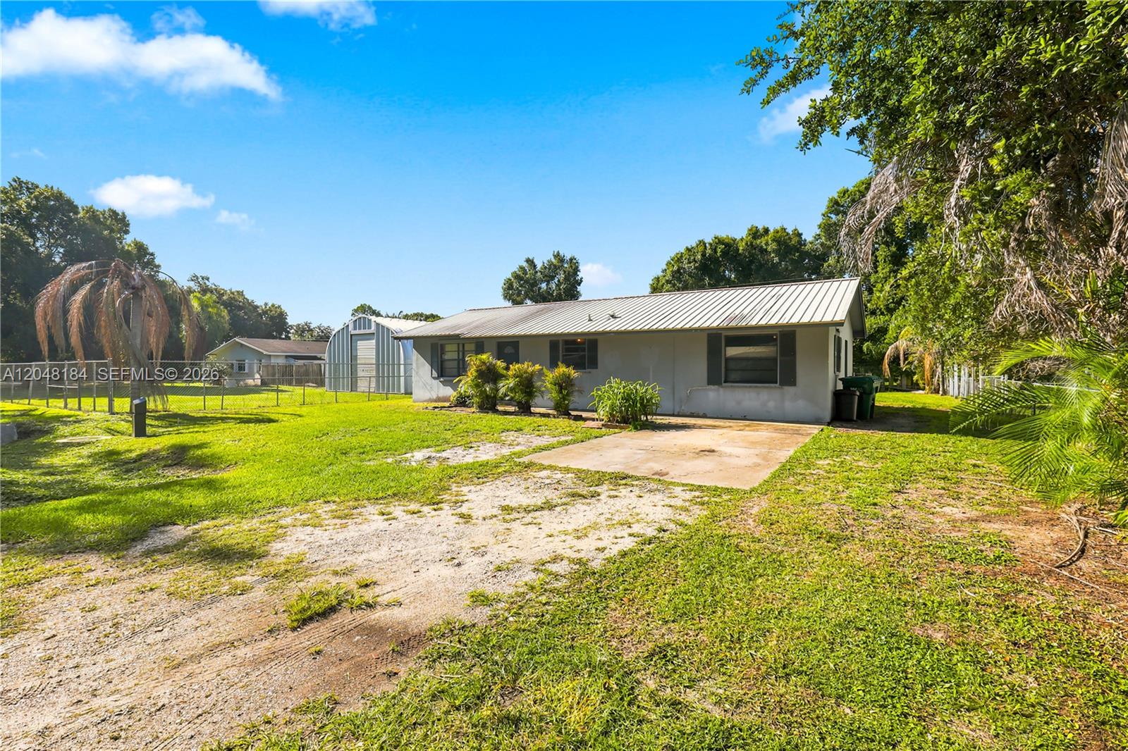 A single-story house with a metal roof and a concrete driveway sits on a lawn — 3524 SW 17th St, Okeechobee FL 34974, OKEECHOBEE, FL