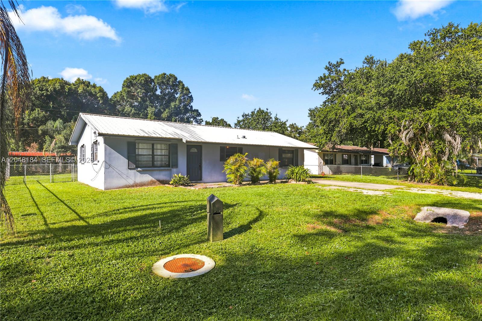 A single-story house with a white metal roof sits on a grassy lot — 3524 SW 17th St, Okeechobee FL 34974, OKEECHOBEE, FL