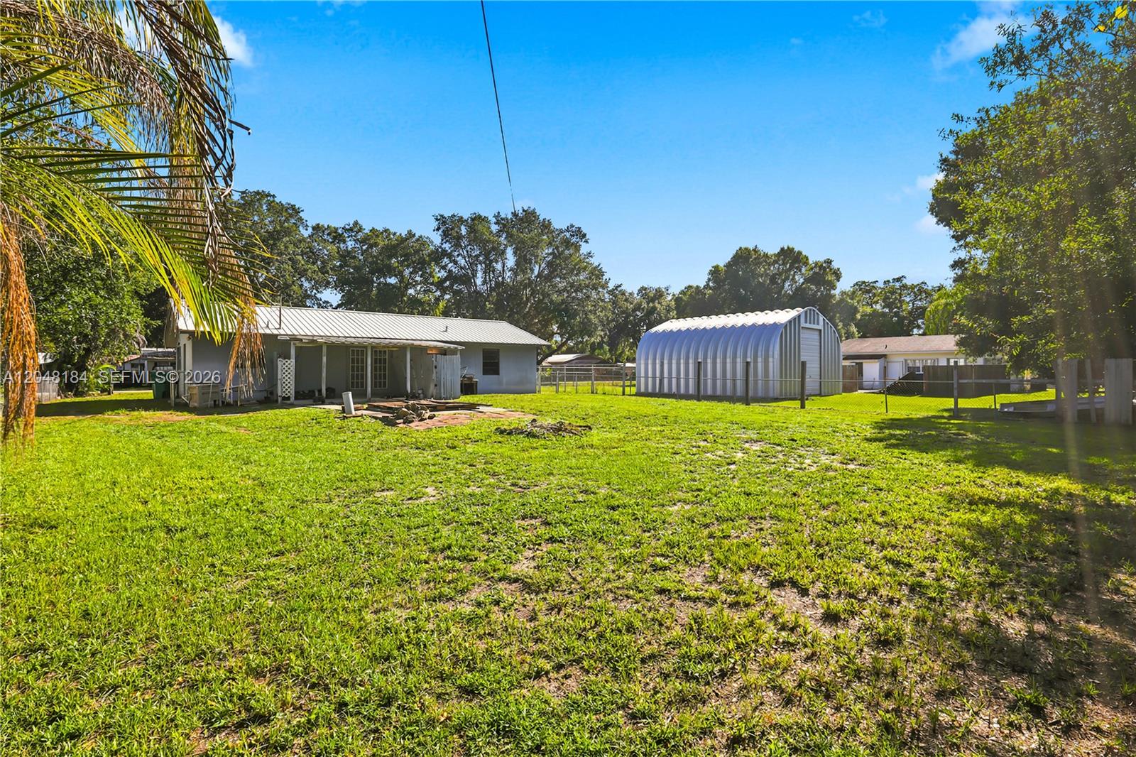 A backyard view features a house with a metal roof, a detached metal shed, and grass — 3524 SW 17th St, Okeechobee FL 34974, OKEECHOBEE, FL
