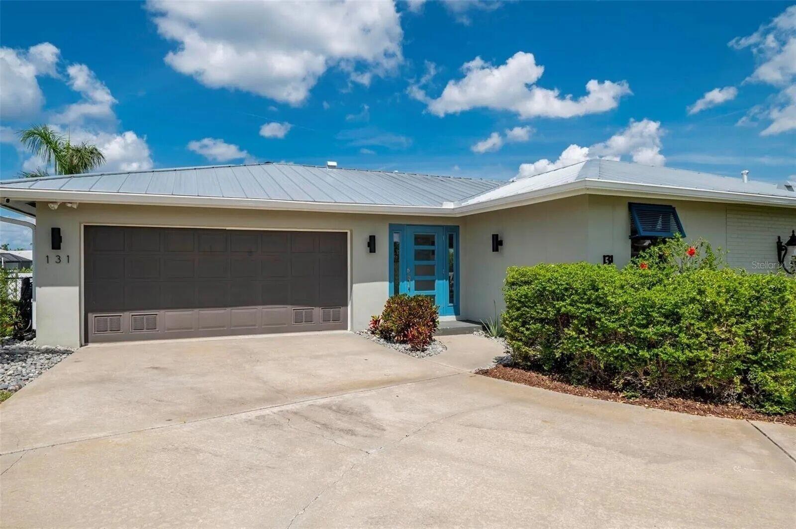 A single-story house with a metal roof, a brown garage door, and a blue front door — 131 Casa Lane, Punta Gorda FL 33950, PUNTA GORDA, FL