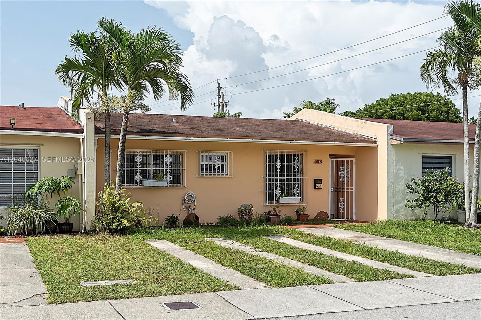 A single-story peach-colored house features a brown roof, security bars on windows, and palm trees — 10112 SW 23rd St, Miami FL 33165, MIAMI, FL
