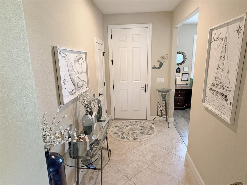 An entryway features tile flooring, a white front door, and nautical-themed wall art — 715 ASTURIAS ROAD, DAVENPORT, FL