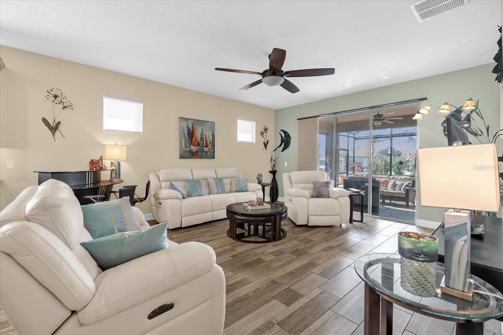 A living room features white leather furniture, a ceiling fan, and tile flooring — 715 ASTURIAS ROAD, DAVENPORT, FL