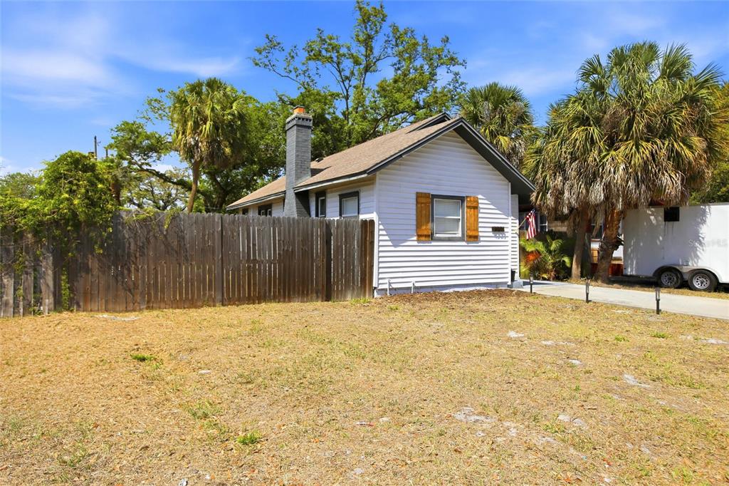 A small white house with a gray chimney and wooden shutters sits behind a wooden fence — 4551 19TH AVENUE S, ST PETERSBURG, FL