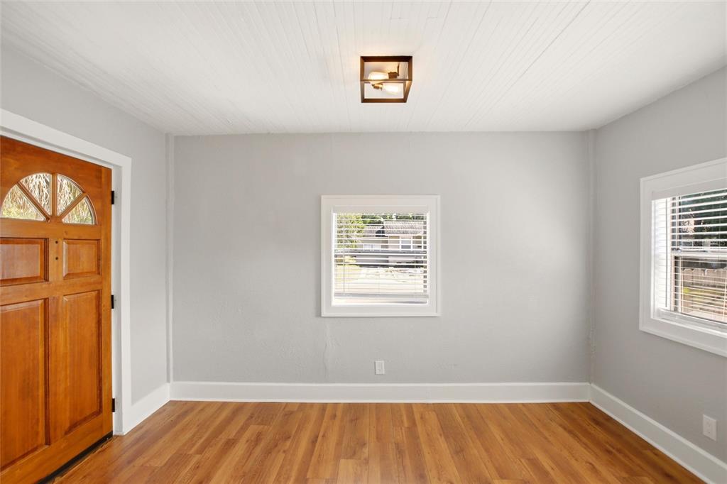 An empty room with gray walls, wood flooring, a wooden door, and two windows — 4551 19TH AVENUE S, ST PETERSBURG, FL