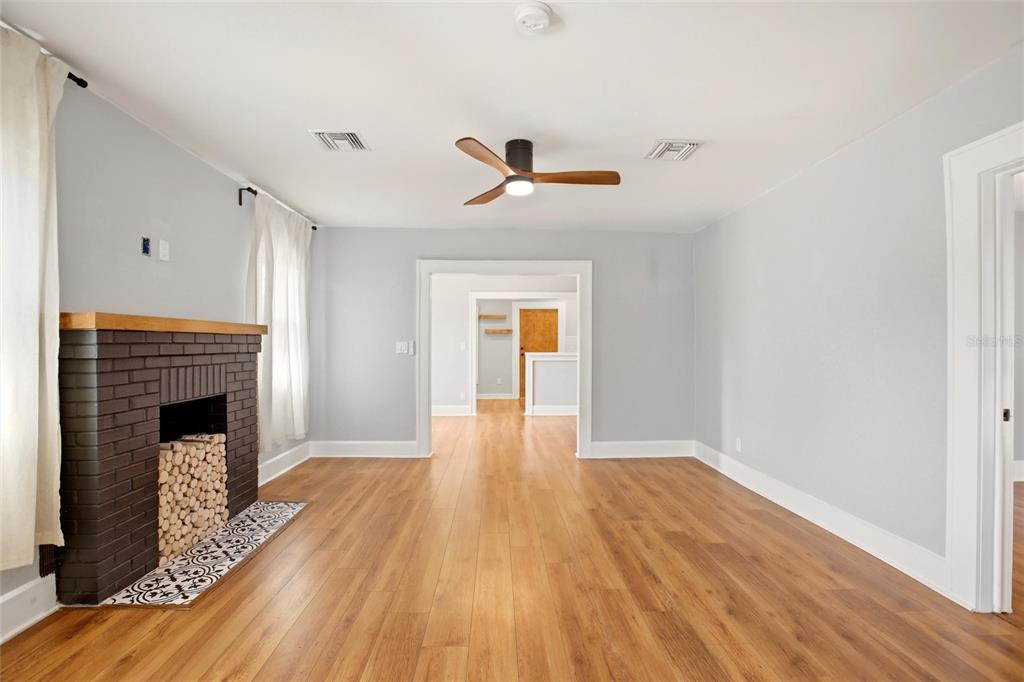 A living room with light gray walls, wood flooring, and a dark brick fireplace — 4551 19TH AVENUE S, ST PETERSBURG, FL