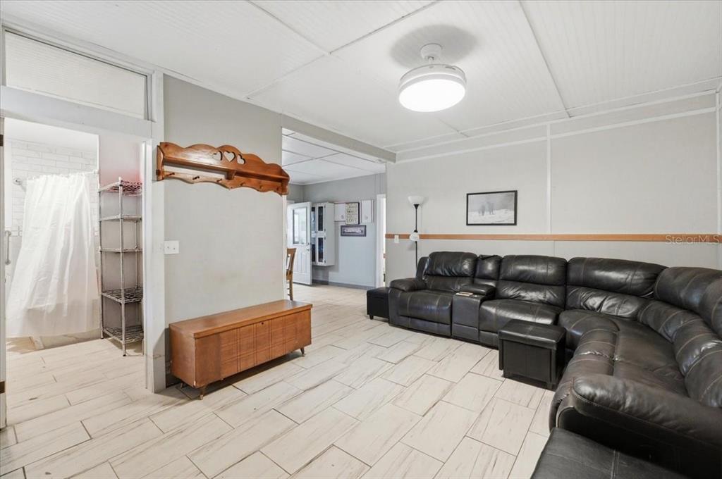 A living room features a large black sectional sofa, tile flooring, and a ceiling fan — 1425 PIONEER DRIVE, LAKELAND, FL
