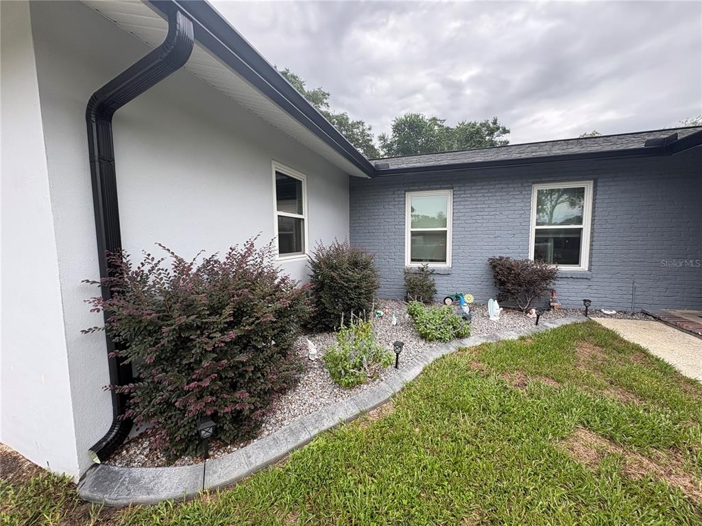 The exterior of a house features a gray brick wall, a white wall, and landscaping — 9216 N ABBOT DRIVE, CITRUS SPRINGS, FL