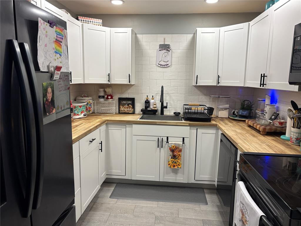 A kitchen features white cabinets, butcher block countertops, a black sink, and subway tile backsplash — 9216 N ABBOT DRIVE, CITRUS SPRINGS, FL
