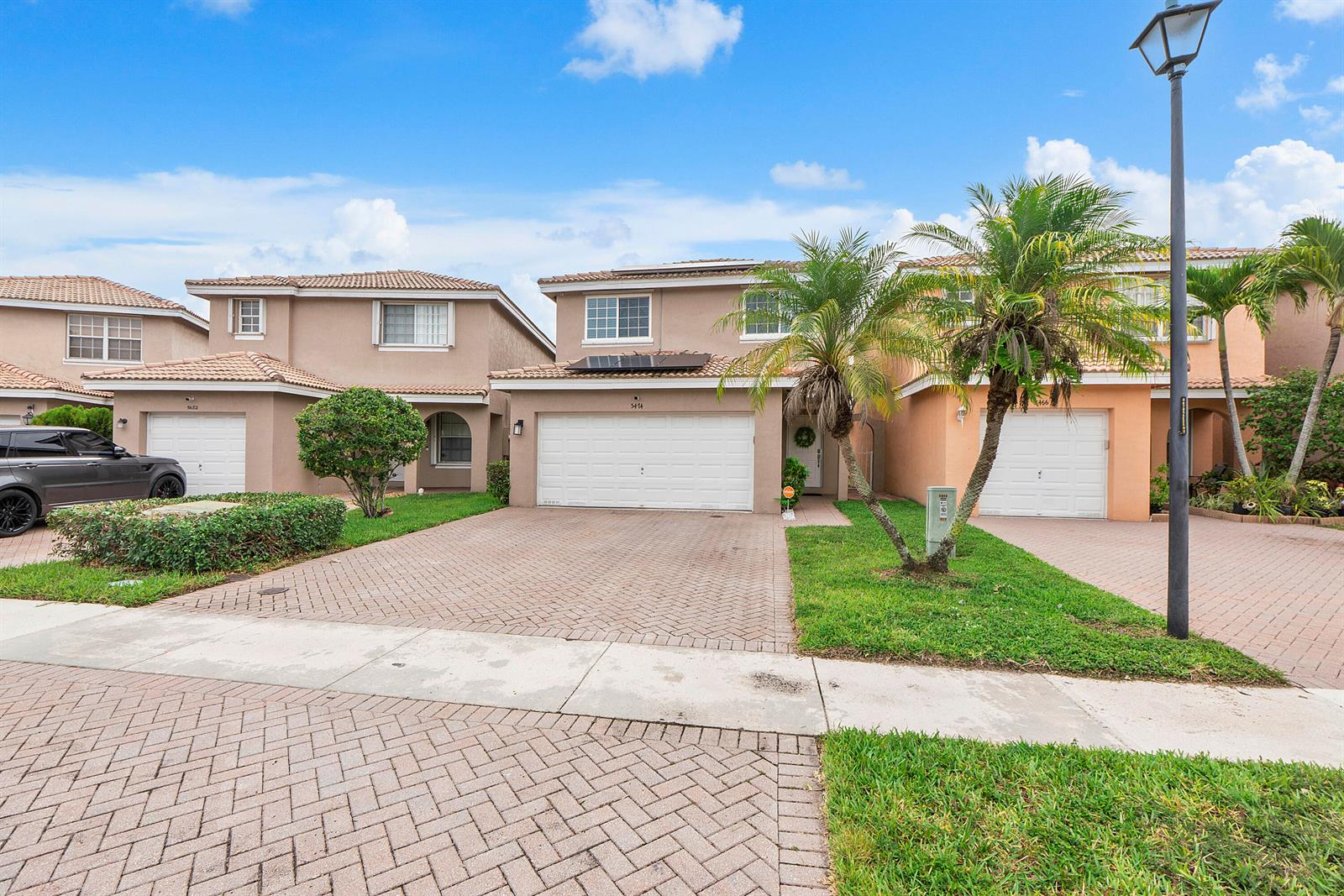 A row of two-story suburban houses with paved driveways and palm trees under a blue sky — 5474 NW 94th Terrace, Sunrise FL 33351, SUNRISE, FL