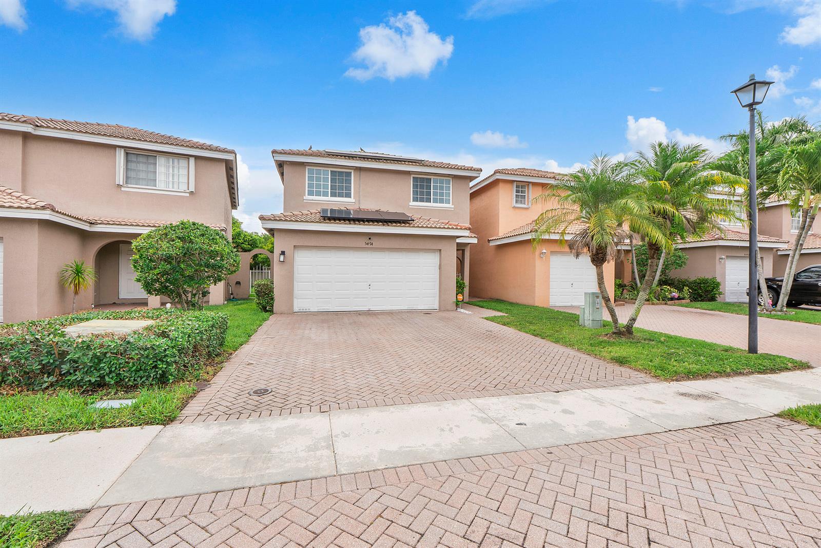 A two-story suburban house features a white garage door, paved driveway, and a tiled roof — 5474 NW 94th Terrace, Sunrise FL 33351, SUNRISE, FL
