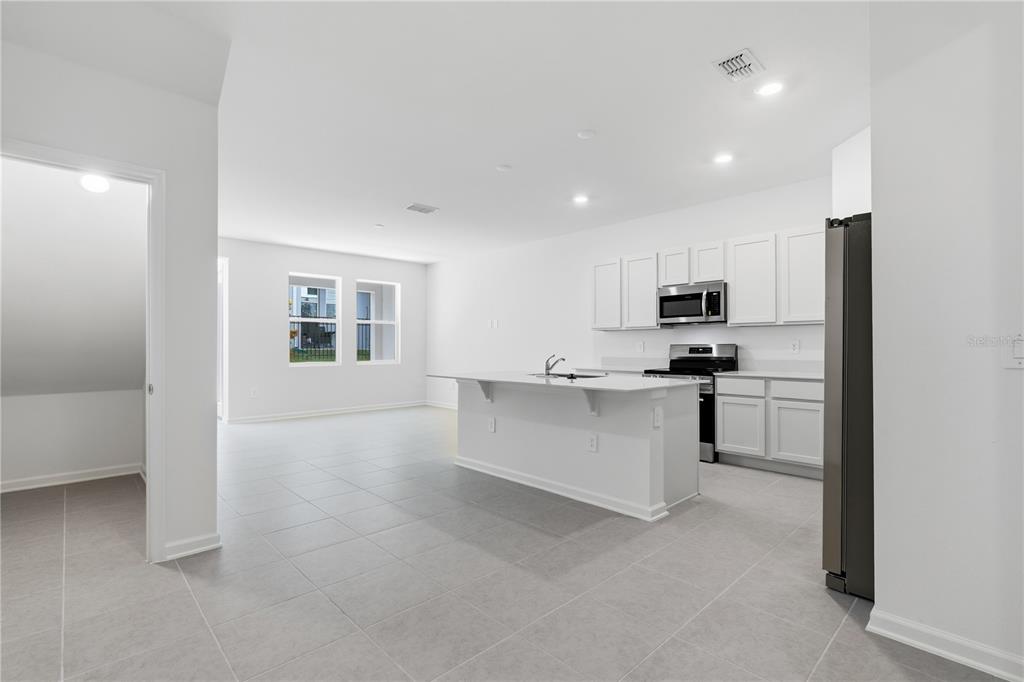 A modern kitchen with white cabinets, a central island, and light tile flooring — 3143 KURTZ TERRACE, DAVENPORT, FL