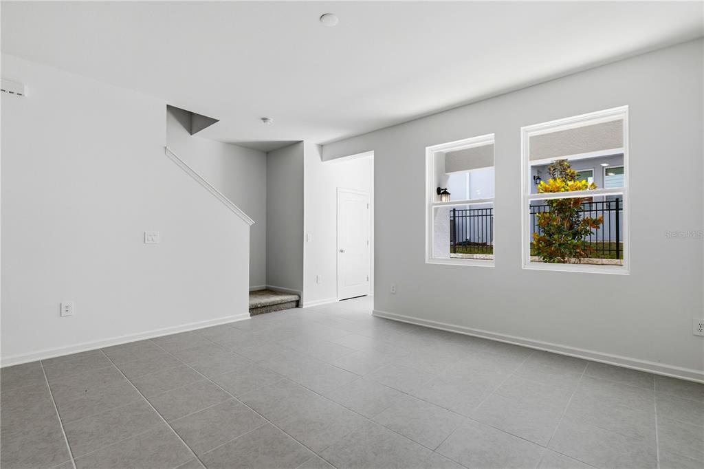 An empty room with gray tile flooring, white walls, and two windows overlooking a fence — 3143 KURTZ TERRACE, DAVENPORT, FL