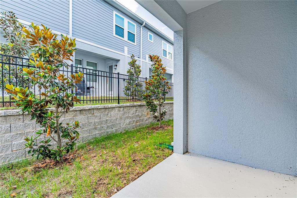 A concrete patio overlooks a grassy yard, a retaining wall, and a black metal fence — 3143 KURTZ TERRACE, DAVENPORT, FL
