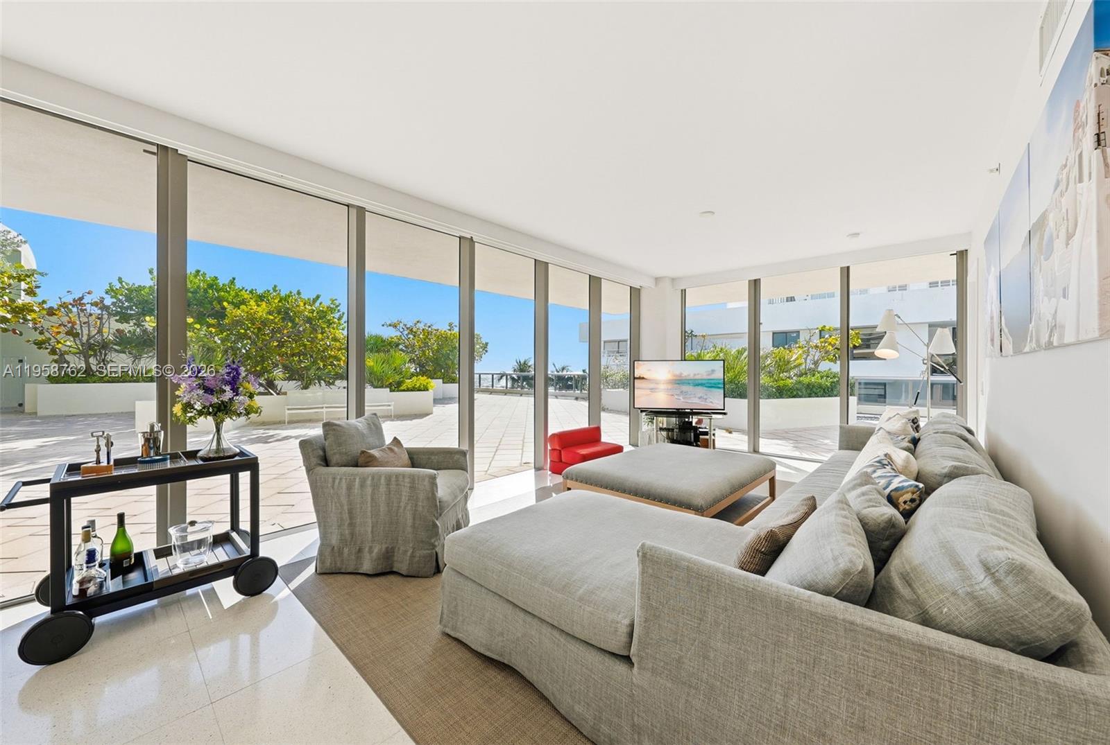 A living room features floor-to-ceiling windows, light tile flooring, and access to a large terrace — 5875 Collins Ave # 502, Miami Beach FL 33140, MIAMI BEACH, FL