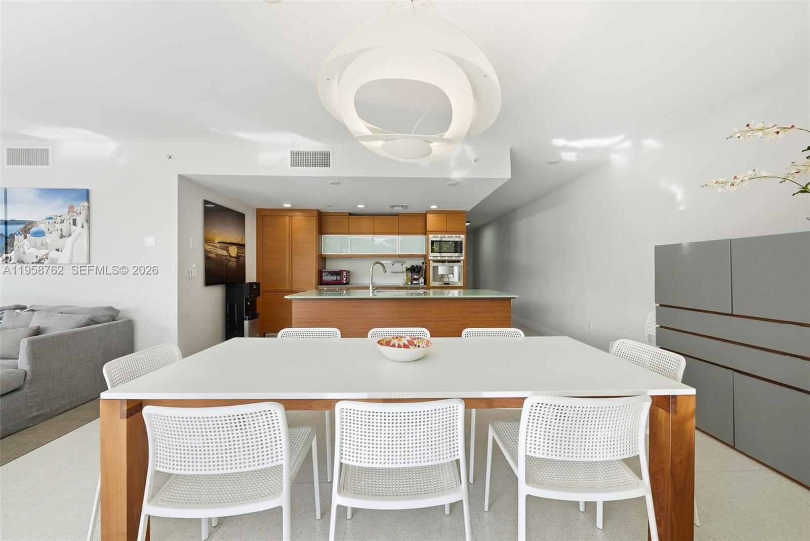 A dining area with a white table and chairs sits in front of a kitchen — 5875 Collins Ave # 502, Miami Beach FL 33140, MIAMI BEACH, FL