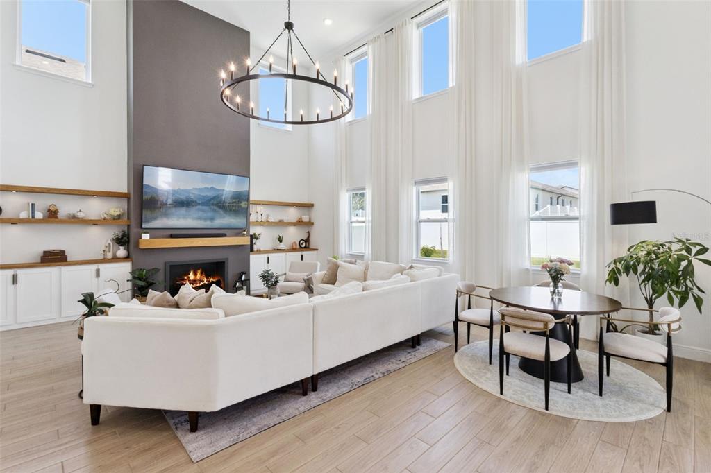 A bright living room features a tall fireplace, large windows, and a dining area — 2185 GOLD DUST DRIVE, MINNEOLA, FL
