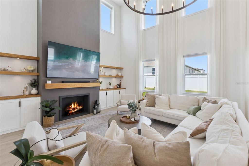 A living room features a fireplace, a large television, and high ceilings with tall windows — 2185 GOLD DUST DRIVE, MINNEOLA, FL