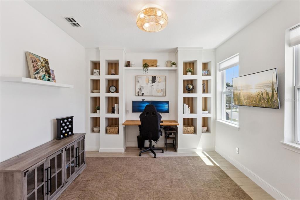 A home office features a built-in desk with shelving, a gaming chair, and a media console — 2185 GOLD DUST DRIVE, MINNEOLA, FL