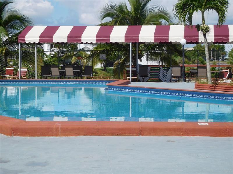 A swimming pool with a red border sits beneath a red and white striped awning — 20337 NE 2nd Avenue, Miami FL 33179, MIAMI, FL