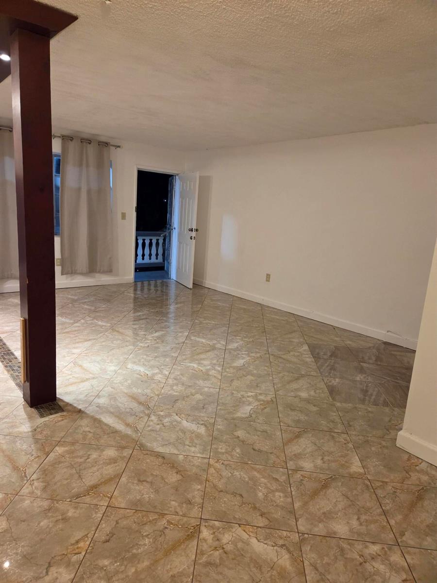 A room with light-colored tile flooring, white walls, and an open door leading outside — 20337 NE 2nd Avenue, Miami FL 33179, MIAMI, FL