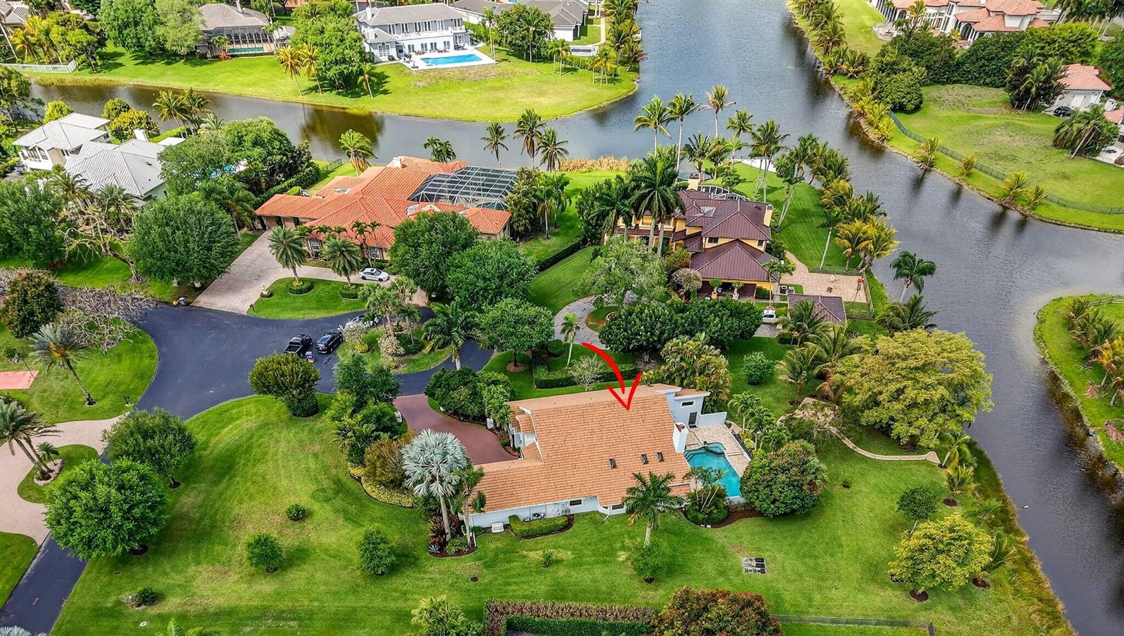 An aerial view shows a house with a tile roof, pool, and surrounding green landscaping — 10655 Rio Hermoso, Delray Beach FL 33446, DELRAY BEACH, FL